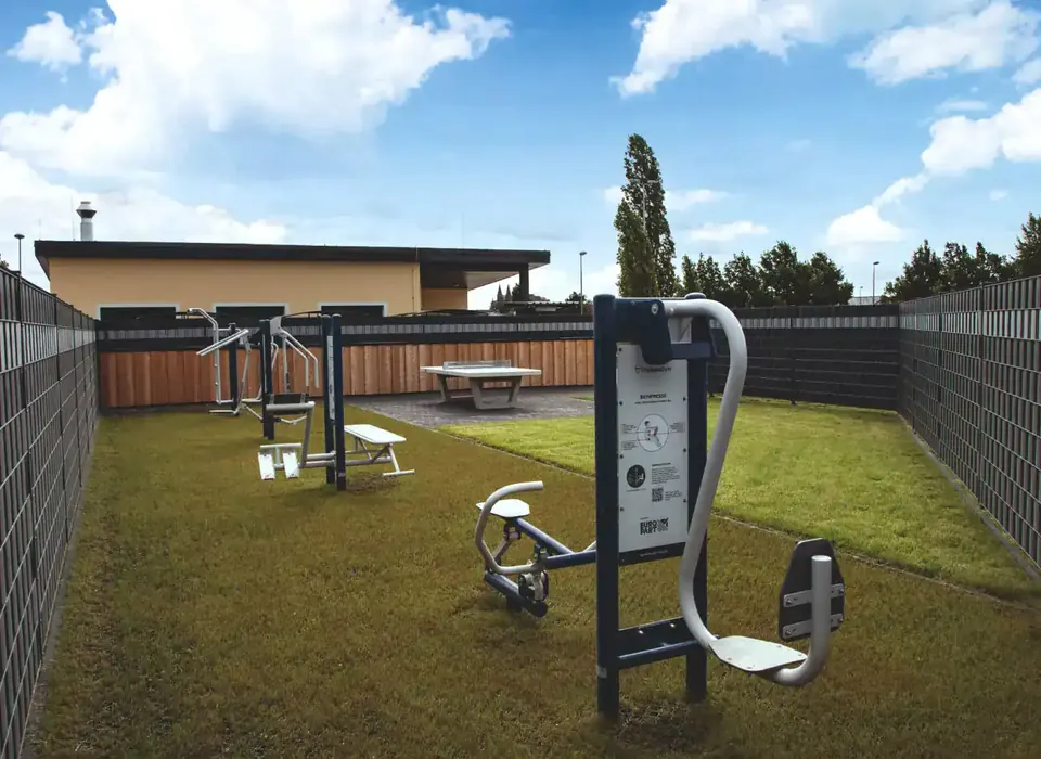 Fitnessgeräte im Freien auf einer umzäunten Rasenfläche